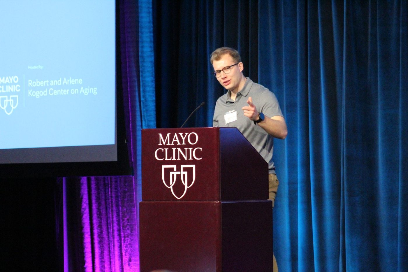 Szczepan Olszewski speaking at a podium marked Mayo Clinic