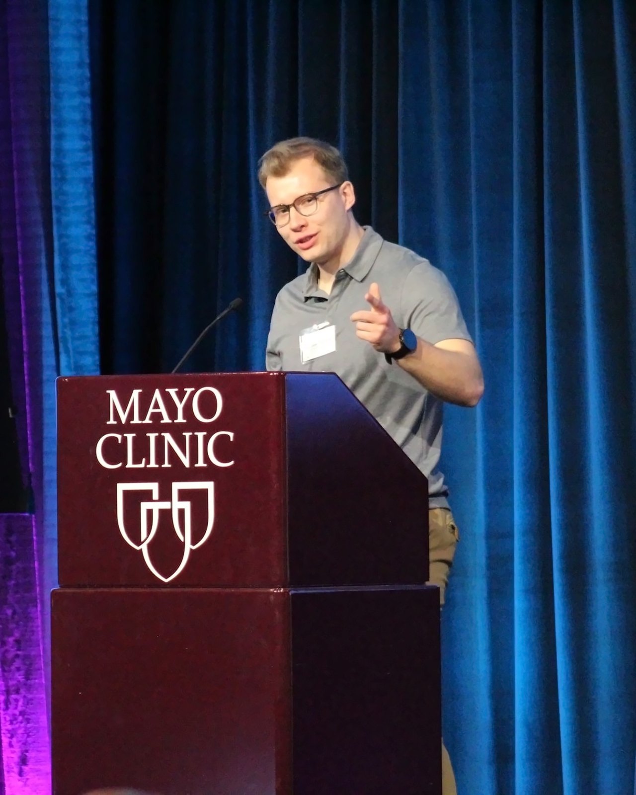 Szczepan Olszewski speaking at a podium marked Mayo Clinic